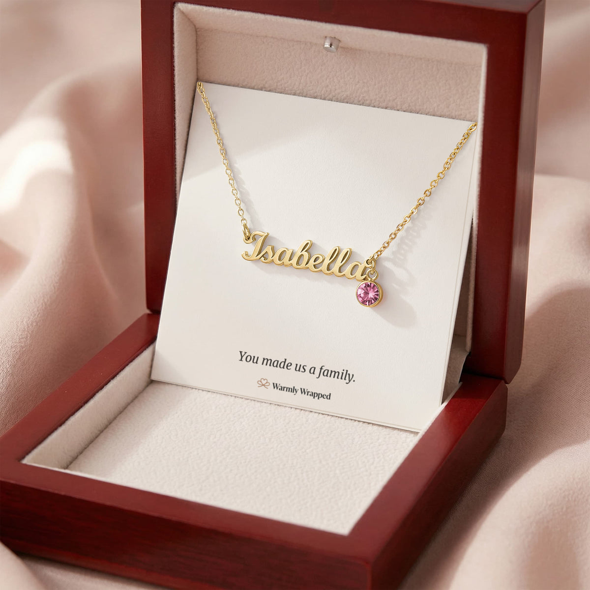What arrives: the name necklace on a card that says “You made us a family.” in a mahogany-style gift box