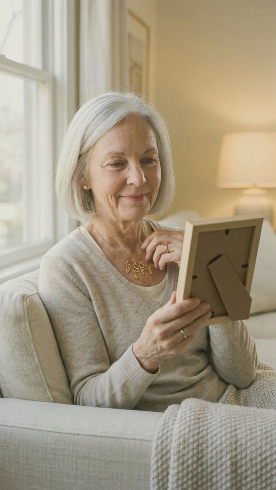 Video: a grandmother looks at a framed photo and touches the names at her collarbone