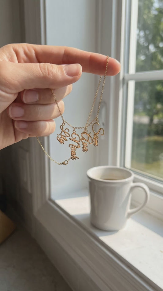 A hand holds the Grandma Necklace with the Grandkids' Names at a sunny kitchen window