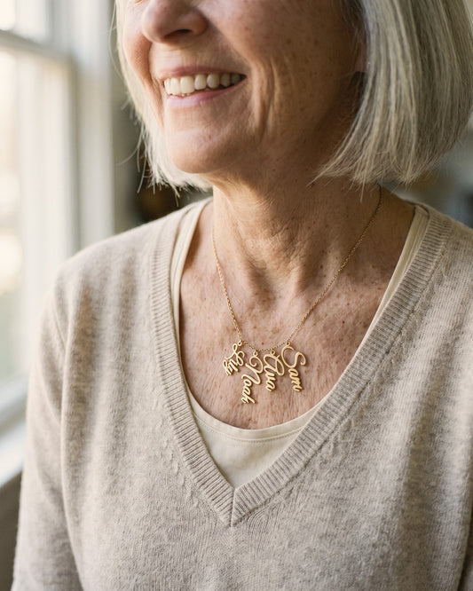 Grandmother wearing a gold necklace with the names Lily, Noah, Ava and Sam hanging side by side