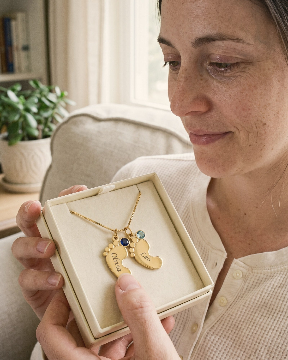 A mom opening the baby-feet necklace in its gift box