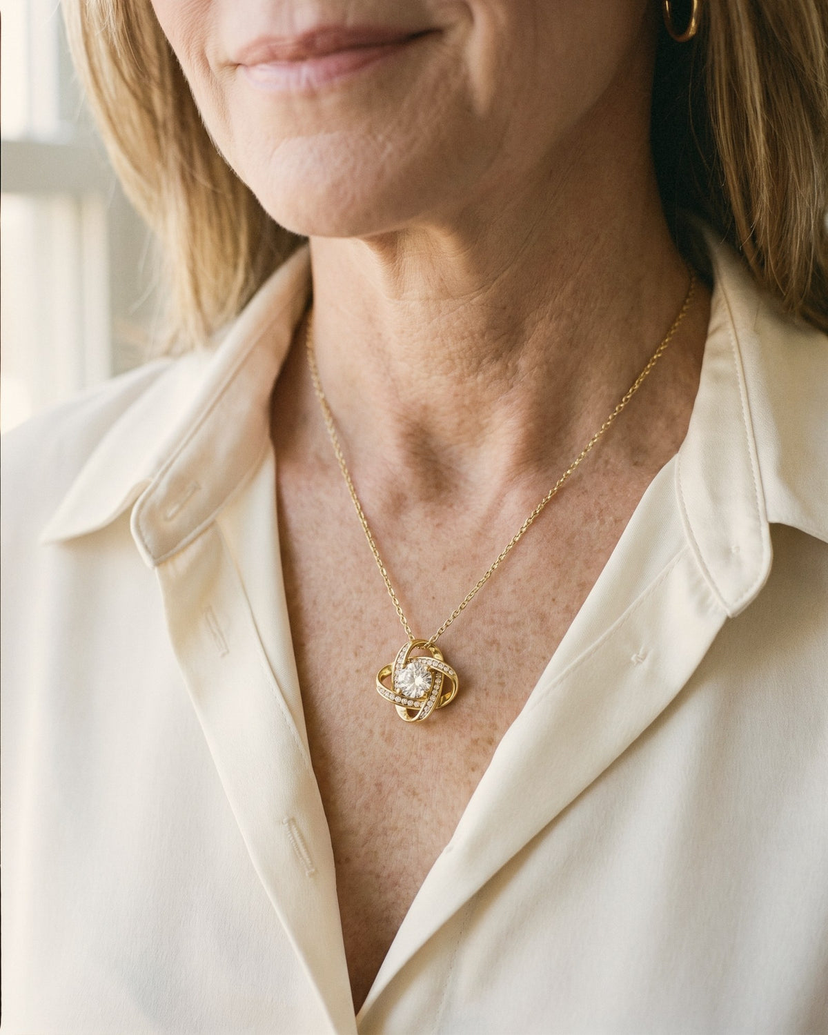 A mom wearing a gold-tone love knot pendant with a center stone