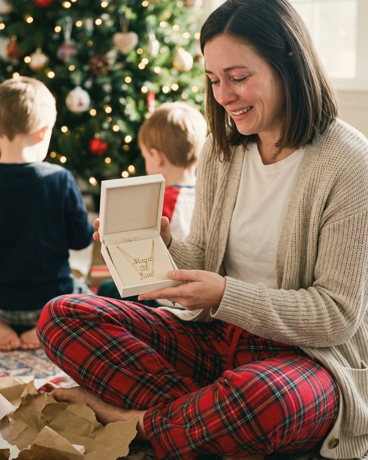 Mom opening her kids' names necklace by the Christmas tree