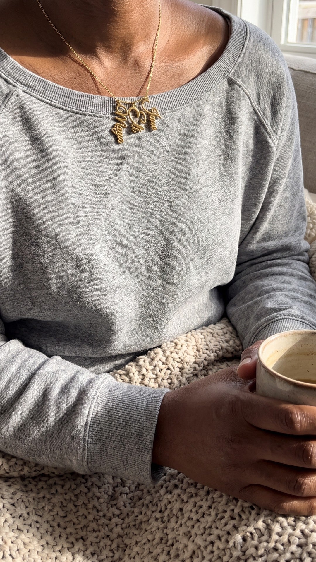 Mom necklace with kids' names, worn at home with a mug