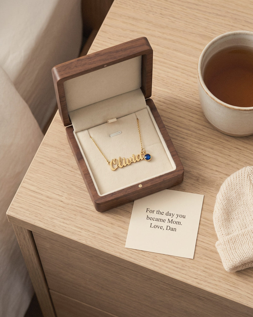 The name necklace in its wooden gift box with a printed card from her partner