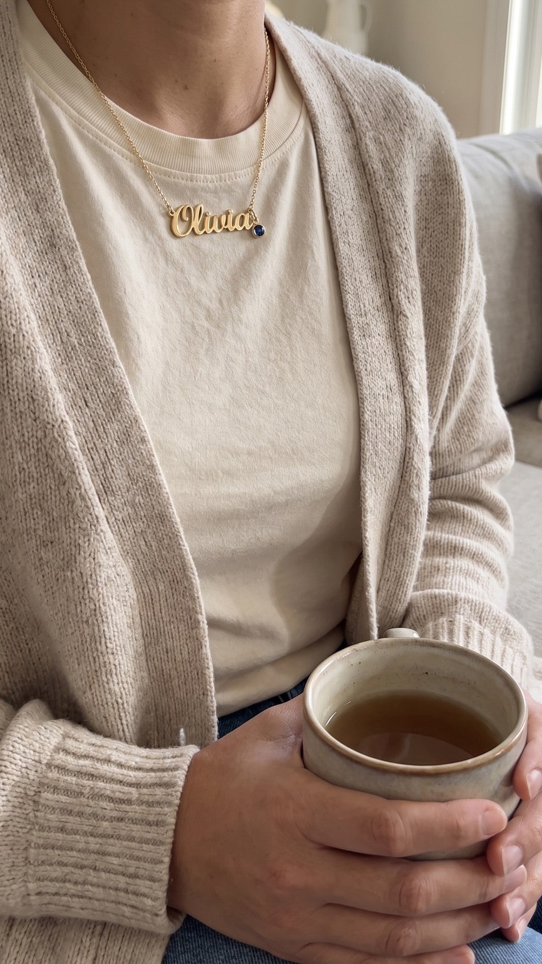 Push present name necklace, worn at home with a mug of tea
